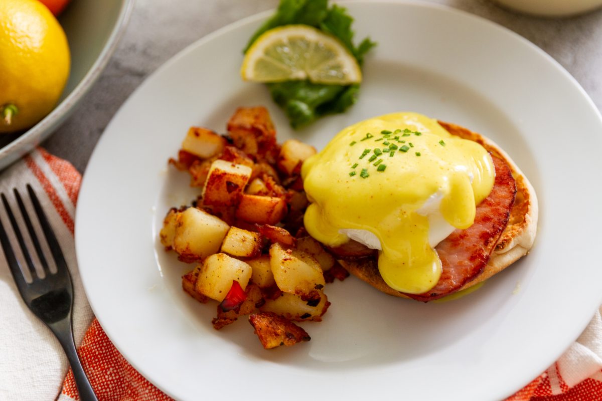 Eggs Benedict topped with Mock Hollandaise made with Blue Plate Mayo, served on a plate with hash browns on the side