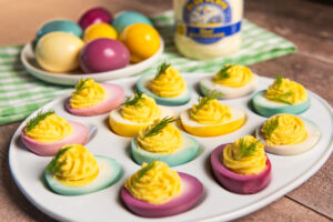 Serving platter of deviled eggs with the whites dyed different colors.