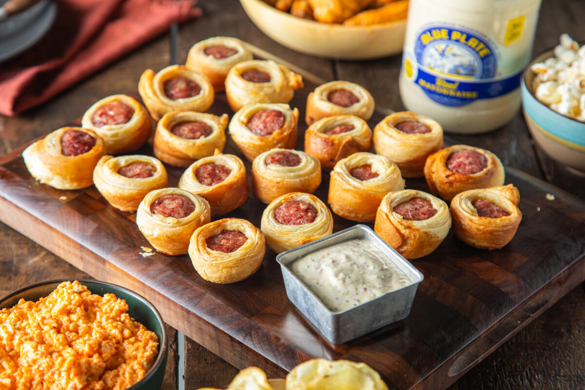 Cajun pigs in a blanket on a serving platter with Creole mustard and mayo dipping sauce.